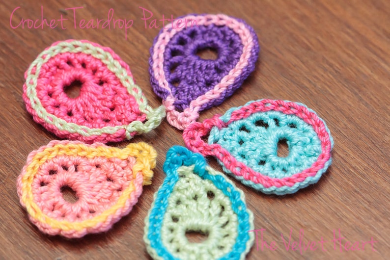 Peut inclure: Cinq formes de larmes en crochet de diff&eacute;rentes couleurs, dont le rose, le violet, le bleu, le vert et le jaune. Chaque larme a un petit cercle au centre.