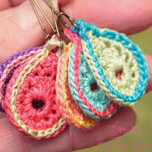 Peut inclure: Un ensemble de cinq marqueurs de points de crochet en forme de fleur dans diff&eacute;rentes couleurs, notamment rose, violet, bleu, vert et jaune. Les marqueurs de points sont attach&eacute;s &agrave; des &eacute;pingles de s&ucirc;ret&eacute;.
