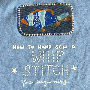 May include: Pale blue fabric with a denim patch showing a vibrant fish design. The patch is stitched with white thread. Text on the fabric reads "HOW TO HAND SEW A WHIP STITCH for beginners" with star accents.