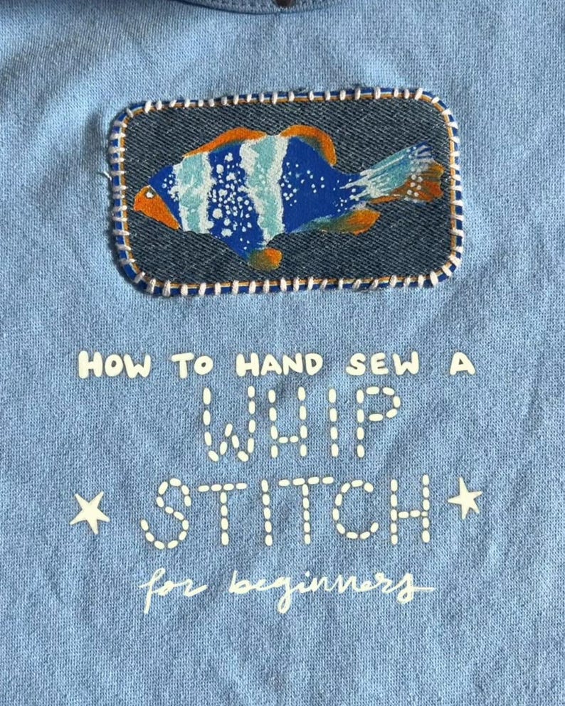 May include: Pale blue fabric with a denim patch showing a vibrant fish design. The patch is stitched with white thread. Text on the fabric reads "HOW TO HAND SEW A WHIP STITCH for beginners" with star accents.