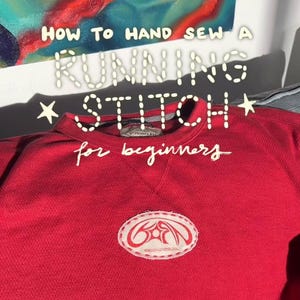 May include: A red sweatshirt with the text "HOW TO HAND SEW A RUNNING STITCH for beginners" in white. The sweatshirt has a white and red patch on the front.