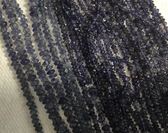 May include: Strands of dark blue iolite gemstone beads. The beads are small, irregular shapes, and vary in shades of blue. The strands are arranged closely together, creating a textured, layered effect. The beads are likely used for jewelry making.