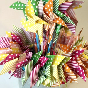 May include: A metal bucket filled with colorful paper pinwheels. The pinwheels are decorated with stripes and polka dots in shades of red, yellow, green, and blue.