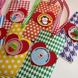 May include: Five Valentine's Day gift bags with different patterns and colors. Each bag has a red heart with a circular sticker featuring a different animal or character. The stickers say "Be Mine! XOXO Chase".