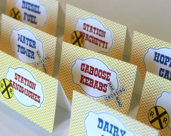 May include: Yellow and white chevron patterned food labels with a train theme. The labels have a red and white railway crossing sign and the text "Diesel Fuel", "Water Tower", "Station Sandwiches", "Station Spaghetti", "Caboose Kebabs", "Hopper Car", "Dairy", "Coal Car".
