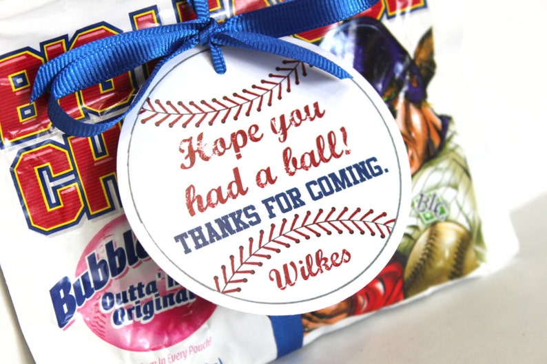 Peut inclure: Une &eacute;tiquette ronde blanche avec un motif de baseball et le texte "Hope you had a ball! Thanks for coming. Wilkes". L'&eacute;tiquette est attach&eacute;e &agrave; un sac blanc avec un motif de joueur de baseball par un ruban bleu.