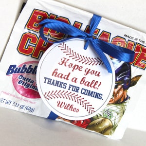 Peut inclure: Une &eacute;tiquette ronde blanche avec des coutures de baseball rouges et bleues autour du bord. L'&eacute;tiquette porte le texte "Hope you had a ball! Thanks for coming. Wilkes" imprim&eacute; dessus. L'&eacute;tiquette est attach&eacute;e &agrave; un sac blanc de chewing-gum avec un ruban bleu.