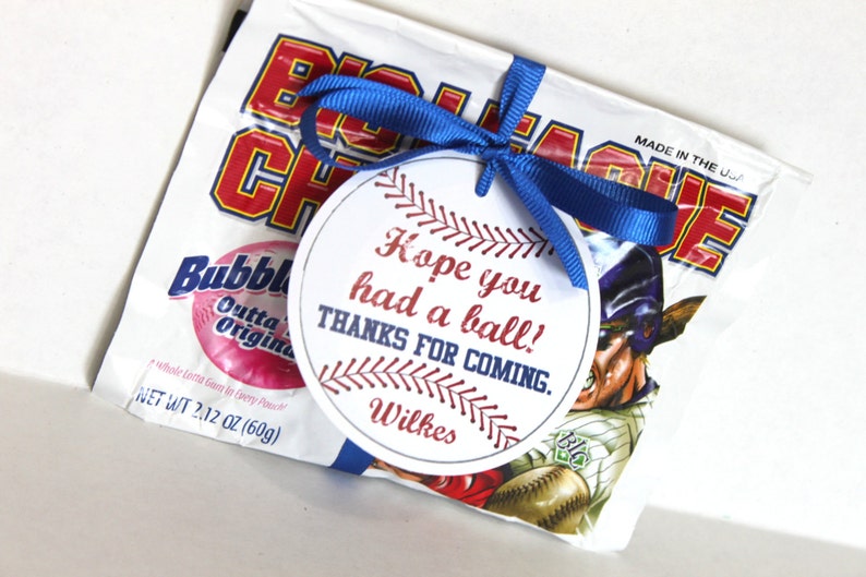 Peut inclure: Une &eacute;tiquette ronde blanche avec des coutures de baseball rouges et bleues autour du bord. L'&eacute;tiquette porte le texte "Hope you had a ball! Thanks for coming. Wilkes" imprim&eacute; dessus. L'&eacute;tiquette est attach&eacute;e &agrave; un sac blanc de chewing-gum avec un ruban bleu.