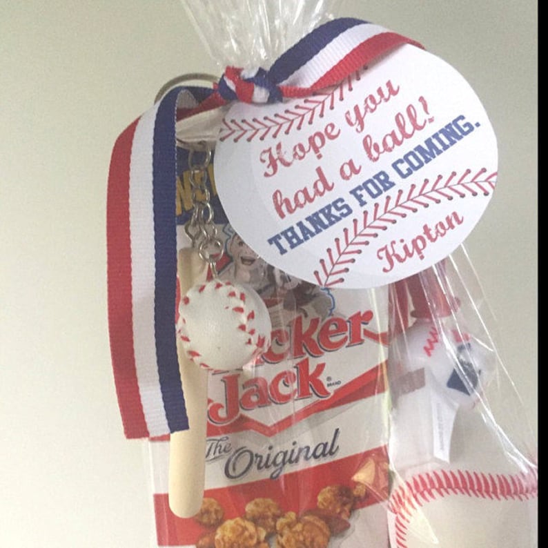 Peut inclure: Un sac de f&ecirc;te sur le th&egrave;me du baseball blanc et rouge avec une &eacute;tiquette blanche qui dit "J'esp&egrave;re que vous avez pass&eacute; un bon moment ! Merci d'&ecirc;tre venu. Kipton". Le sac contient un petit porte-cl&eacute;s de batte de baseball, un petit ballon de baseball, un sac de ma&iuml;s souffl&eacute; Cracker Jack et un petit ballon de baseball blanc.