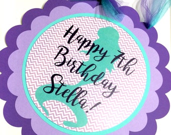 May include: Purple and teal mermaid-themed birthday party door sign with the text "Happy 7th Birthday Stella!"