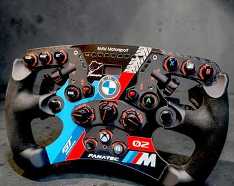 Puede incluir: Un volante de carreras negro y gris con detalles en rojo, azul y blanco. El volante presenta múltiples botones, perillas y el logotipo de BMW Motorsport. El volante tiene un agarre texturizado y el texto "FANATEC" es visible.