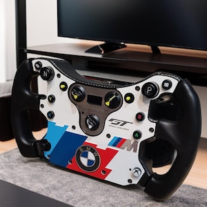 May include: A racing steering wheel with a white face, black grips, and a BMW logo. The wheel has buttons, dials, and the text "GT World Challenge". The design incorporates blue, red, and silver accents.