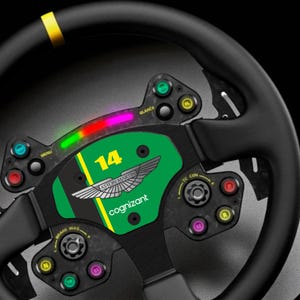 May include: A black steering wheel with green and yellow accents. The wheel features the Aston Martin Cognizant logo, the number 14, and various buttons. A multi-colored LED light bar is at the top. The wheel is designed for racing.