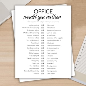 Op de afbeelding: Een wit papier met de tekst "OFFICE would you rather" in het zwart, met een lijst met werkgerelateerde keuzes. Het papier ligt op een houten bureau met een laptop en een notitieblok op de achtergrond. De tekst staat in een duidelijk leesbaar lettertype.