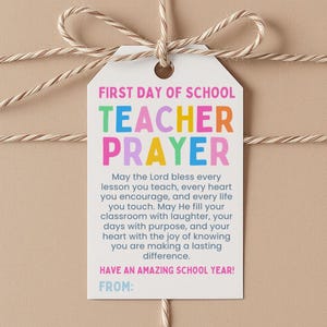 May include: A white rectangular gift tag with a hole at the top, tied with tan twine. The text reads: FIRST DAY OF SCHOOL TEACHER PRAYER, followed by a prayer message and HAVE AN AMAZING SCHOOL YEAR! FROM: at the bottom in colorful lettering.