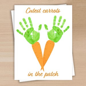 May include: A white card with the text "Cutest carrots in the patch" in orange. The card features green handprints forming carrot tops above two orange carrot illustrations.