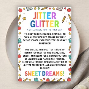 May include: A rectangular card with the text JITTER GLITTER A LITTLE MAGIC FOR THE FIRST DAY! IT'S OKAY TO FEEL EXCITED, NERVOUS, OR EVEN A LITTLE WORRIED BEFORE THE FIRST DAY OF SCHOOL. SWEET DREAMS! The border features colourful apples, pencils, and books.