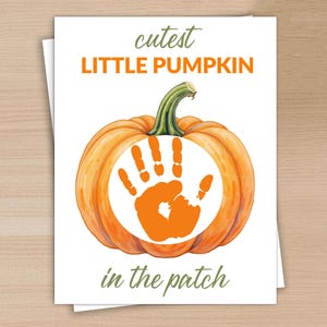 May include: A greeting card featuring a watercolor illustration of an orange pumpkin with a green stem. The pumpkin has an orange handprint in the center, with the words "cutest LITTLE PUMPKIN in the patch" in orange and green text.