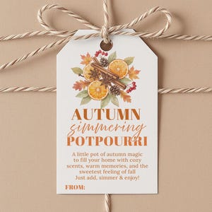 Op de afbeelding: Een wit rechthoekig cadeaulabel met een aquarelillustratie van sinaasappelschijfjes, kaneelstokjes, dennenappels en herfstbladeren. De tekst luidt AUTUMN simmering POTPOURRI, gevolgd door beschrijvende tekst en een FROM:-regel.