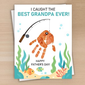 May include: A greeting card featuring the text I CAUGHT THE BEST GRANDPA EVER! and HAPPY FATHER'S DAY! The design includes a brown fishing rod, an orange handprint shaped like a fish, green seaweed, coral, and two small colorful fish.
