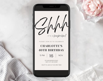 May include: A smartphone displays a digital invitation for Charlotte's 40th birthday. The invitation features the word "Shhh" in a bold, black script, followed by "It's a Surprise!" and event details. A pink rose and a striped cloth are in the background.
