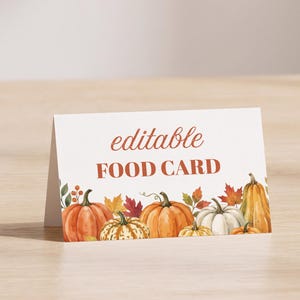 May include: A white folded card featuring the text "editable FOOD CARD" in orange and brown lettering. The bottom border displays a watercolor illustration of various pumpkins, gourds, and autumn leaves in shades of orange, yellow, and white.