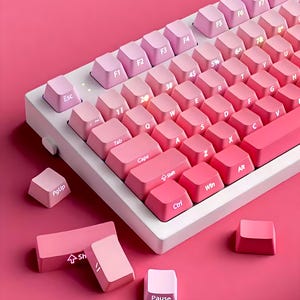 May include: A white keyboard with pink keys. The keys have a gradient color effect, starting with a light pink and fading to a darker pink. The keyboard has a variety of keys, including function keys, number keys, letter keys, and special keys. The keyboard is on a pink surface.