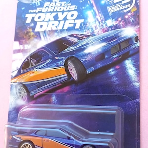 Op de afbeelding: Een Hot Wheels Silver Series gegoten Nissan Silvia (S15) speelgoedauto in blauw en oranje, verpakt op een kaart met The Fast and the Furious: Tokyo Drift branding, 25-jarig jubileumlogo, 2/5 nummering en het Mattel-logo.