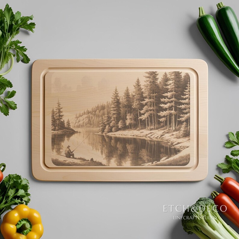 May include: A rectangular wooden cutting board with a sepia-toned engraved image of a person fishing on a lake surrounded by trees. The board has a light wood finish and a recessed juice groove. The text "ETCH&DECO" is at the bottom.
