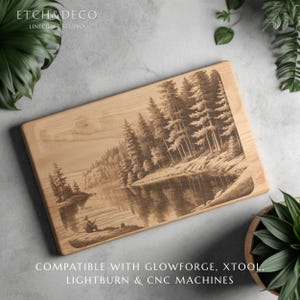 May include: A rectangular wooden cutting board with a detailed laser-etched landscape scene of a lake and forest. The artwork depicts a person fishing on the shore. The text "ETCH & DECO" and "LINECRAFT STUDIO" are at the top.