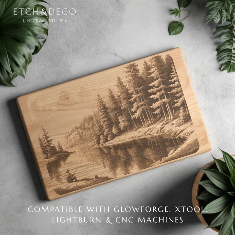 May include: A rectangular wooden cutting board with a detailed laser-etched landscape scene of a lake and forest. The artwork depicts a person fishing on the shore. The text "ETCH & DECO" and "LINECRAFT STUDIO" are at the top.