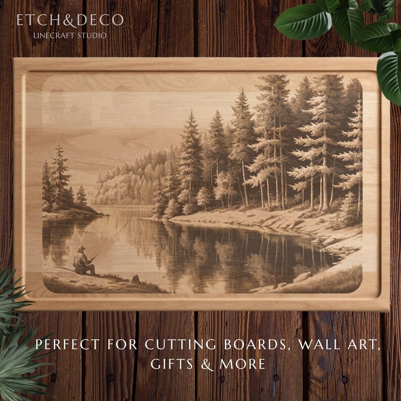 May include: Wooden cutting board with a detailed engraved landscape scene of a person fishing on a lake surrounded by trees. The board has a light wood finish and a recessed edge. The text "ETCH&DECO LINECRAFT STUDIO" is at the top.