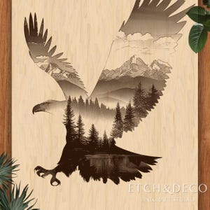 Może przedstawiać: Drewniane dzieło sztuki ściennej z laserowo wyciętym wzorem lecącego orła. Skrzydła orła wypełnione są krajobrazem gór, drzew i jeziora. Dzieło podpisane "ETCH & DECO" z "LINECRAFT STUDIO" poniżej.