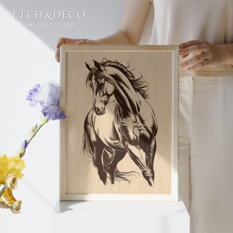 May include: Wooden framed art print featuring a detailed illustration of a horse in a running pose. The artwork is in shades of brown and tan, with the text "ETCH&DECO LINE CRAFT STUDIO" in the upper left corner. The print is held up by a person.