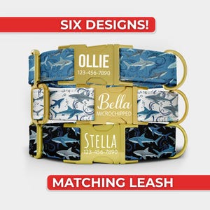 May include: Three dog collars with shark patterns and gold-colored buckles. The top collar features the name OLLIE and a phone number. The middle collar displays the name Bella and the word MICROCHIPPED. The bottom collar shows the name STELLA and a phone number. Text reads SIX DESIGNS! and MATCHING LEASH.