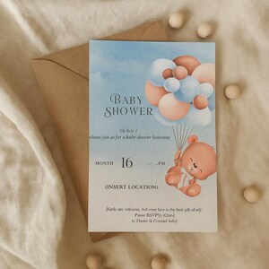 Könnte beinhalten: Babyparty-Einladung mit Aquarelldesign. Die Einladung zeigt einen Teddybären, der Luftballons hält, mit dem Text "Baby Shower" und dem Datum "16". Enthält einen Kraftpapierumschlag und Holzperlen.