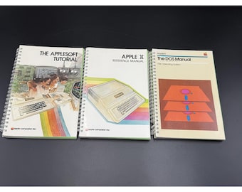 May include: Three vintage Apple computer manuals. The manuals are spiral-bound and feature colorful illustrations and text. Titles include "The Applesoft Tutorial," "Apple II Reference Manual," and "The DOS Manual."