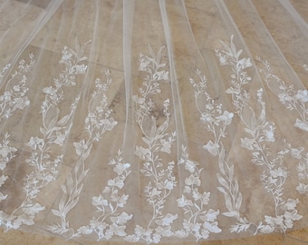 May include: White tulle fabric with delicate floral embroidery. The fabric is sheer and has a soft, flowing texture.