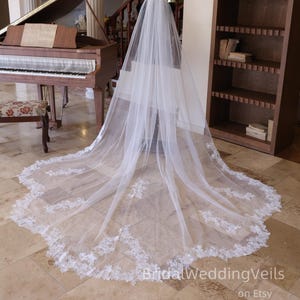 Peut inclure: Un long voile de mariée blanc avec une délicate bordure en dentelle. Le voile est présenté dans une pièce avec un piano et une bibliothèque. Le texte "BridalWeddingVeils on Etsy" est visible en bas.
