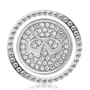 May include: Silver car emblem with a crystal-encrusted Infiniti logo. The emblem is surrounded by a ring of smaller crystals.