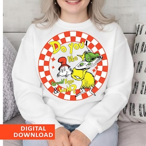 May include: White sweatshirt featuring a colorful graphic from the children's book "Green Eggs and Ham." The design includes the text "Do you like Green Eggs & ham?" in a playful font, surrounded by a red and white checkered circle.