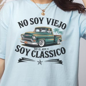 May include: Light blue t-shirt with the text "NO SOY VIEJO SOY CLASSICO" and a graphic of a vintage teal pickup truck. The truck has a skeleton driver and palm trees. The shirt also has PNG, SVG, EPS, and PDF icons.
