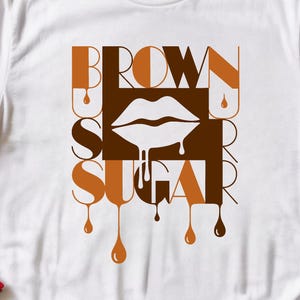 Peut inclure: T-shirt blanc avec l'inscription "BROWN SUGAR" en lettres marron et beige. Le motif comprend une bouche blanche et des gouttes marron. Le t-shirt est fait d'une matière douce.