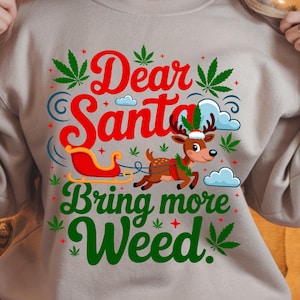 May include: Beige sweatshirt with a Christmas-themed graphic. The design features the text "Dear Santa Bring more Weed" in red and green, with a reindeer pulling a sleigh. Marijuana leaves are incorporated into the design.