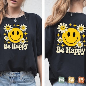 Könnte beinhalten: Schwarzes T-Shirt mit einem Retro-Design mit einem gelben Smiley, Gänseblümchen und Sternen. Die Worte "Be Happy" sind unter der Grafik in einer Vintage-Schriftart aufgedruckt. Das Design befindet sich auf der Vorder- und Rückseite des T-Shirts.