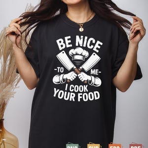 Könnte beinhalten: Schwarzes T-Shirt mit dem weißen Text "BE NICE TO ME I COOK YOUR FOOD". Das Design umfasst gekreuzte Hackmesser, eine Kochmütze und Hände, die die Hackmesser halten. Das Shirt hat auch PNG-, SVG-, EPS- und PDF-Symbole.