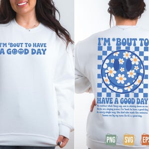 May include: White sweatshirt with the text "I'M 'BOUT TO HAVE A GOOD DAY" in blue. The back features a blue smiley face with daisy accents and the words "HAVE A GOOD DAY".