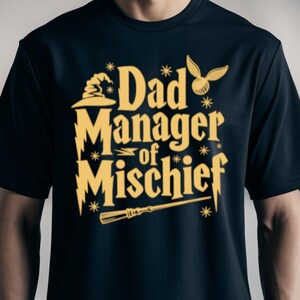 May include: A black t-shirt with a gold graphic that says "Dad Manager of Mischief" with a wizard's hat, a lightning bolt, a wand, and a golden snitch.