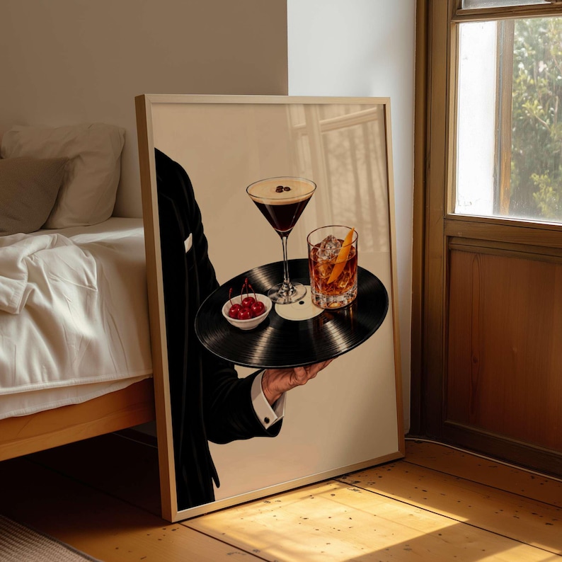 Pode incluir: Uma impress&atilde;o de arte emoldurada que retrata uma pessoa com um casaco de fato preto a segurar um disco de vinil preto como tabuleiro. O disco cont&eacute;m um copo de martini com gr&atilde;os de caf&eacute;, um copo de u&iacute;sque com gelo e casca de laranja e cerejas.