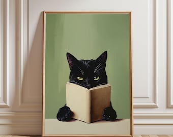 May include: A framed art print featuring a black cat reading a book. The cat is the focal point, with its yellow eyes peering over the open book. The background is a muted green, and the frame is a light brown.